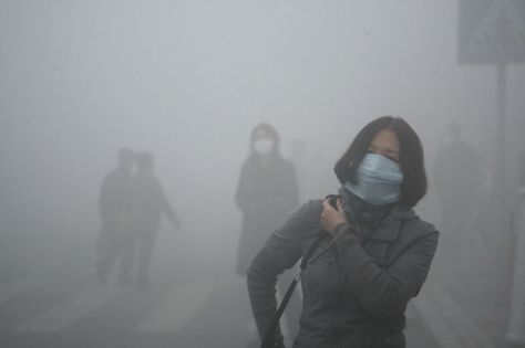 A woman wearing a mask walk through a street covered by dense smog in Harbin, northern China, Monday, Oct. 21, 2013. Visibility shrank to less than half a football field and small-particle pollution soared to a record 40 times higher than an international safety standard in one northern Chinese city as the region entered its high-smog season. (AP Photo/Kyodo News)